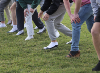 Sprint race participants line up on the grass patch and prepare to take off running in their heels.