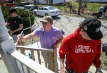 University of Maine student and Theta Chi brother Jake Kelly (center) helps paint the railings with other fraternity brothers outside Families First Community Center in Ellsworth. Photo by Lizzie Heintz.