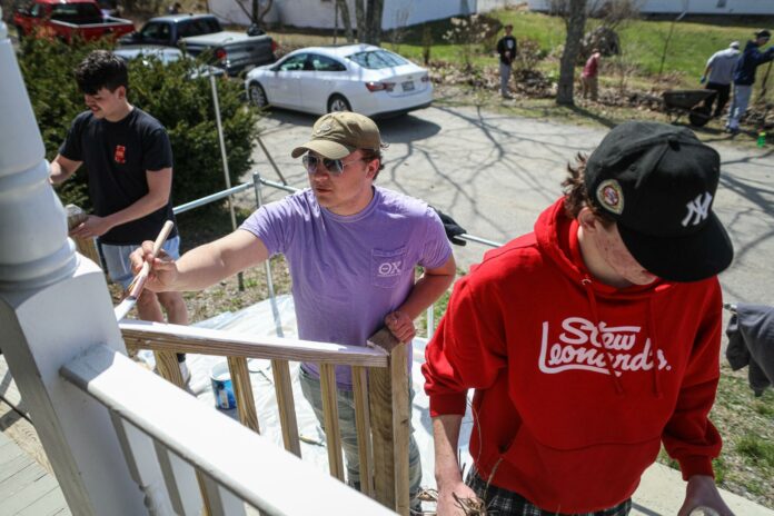 University of Maine student and Theta Chi brother Jake Kelly (center) helps paint the railings with other fraternity brothers outside Families First Community Center in Ellsworth. Photo by Lizzie Heintz.