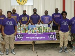 Members of the Omega Lamplighters, front row, and Omega Psi Phi Fraternity Inc., back row, stack food they collected during a food drive for Feed by Faith. Glenda Sanders / The Meridian Star