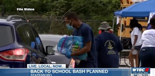 Omega Psi Phi International Fraternity members hand out back packs for back to school.
