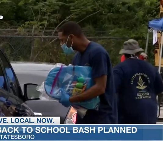 Omega Psi Phi International Fraternity members hand out back packs for back to school.