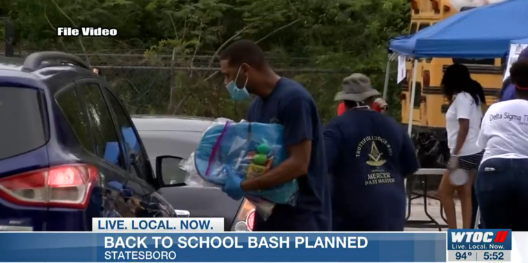 Omega Psi Phi International Fraternity members hand out back packs for back to school.